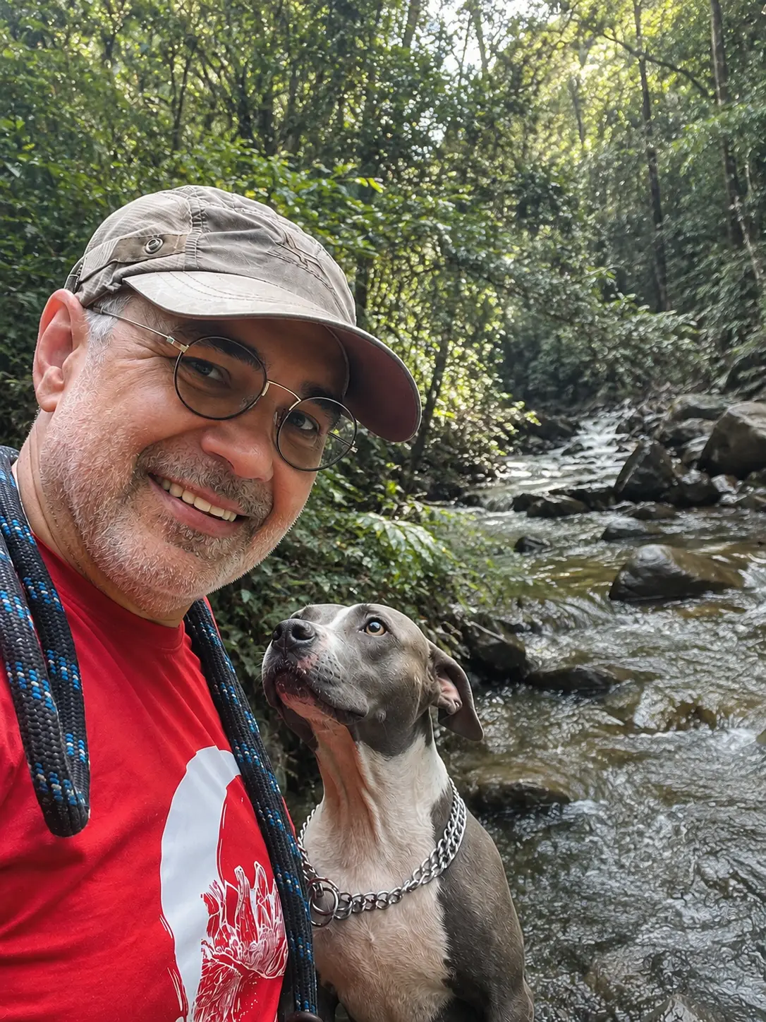Jorge Cavalheiro em trilha à beira de um rio, ao lado de seu cão